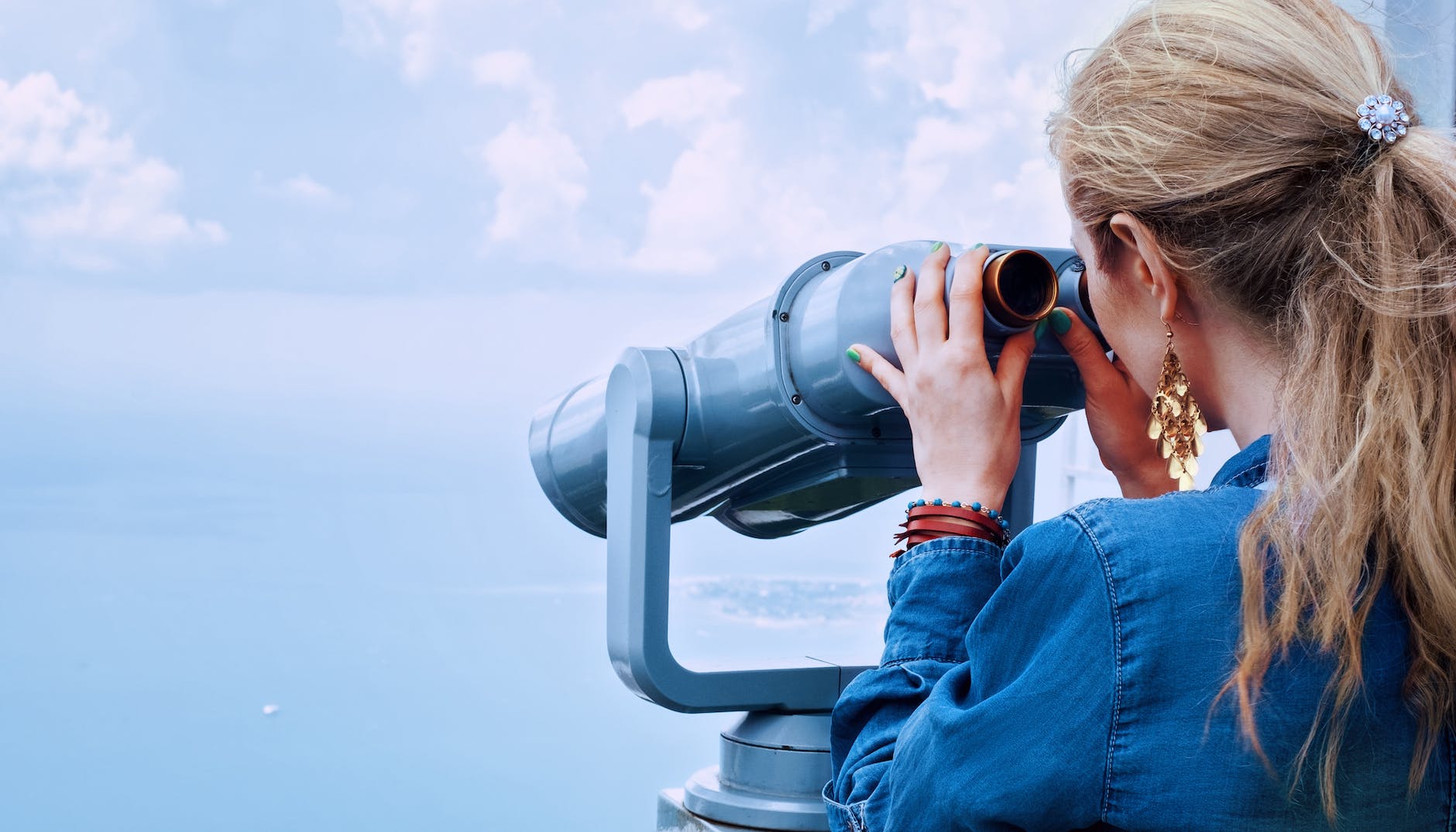 woman in blue denim jacket holding a gray steel tower viewer